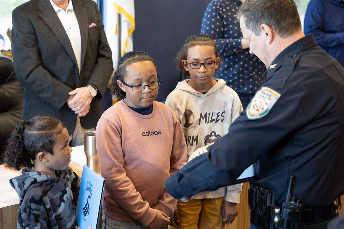 Swansea Chief of Police Matthew Blomberg hands an award to three boys who helped alert police to an active house fire in Swansea, Ill., leading them to save the man trapped inside.