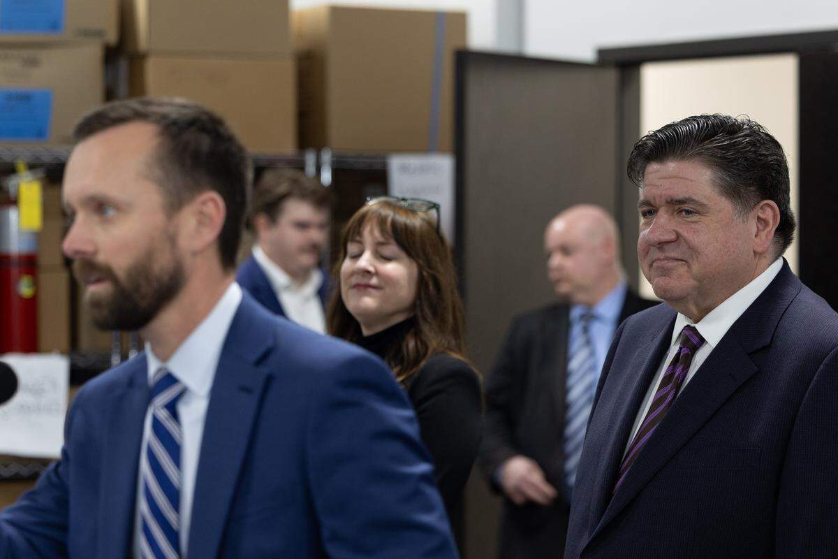 Madison County Board Chairman Chris Slusser moves to speak at the opening of a new TekLab facility in Collinsville while Gov. J.B. Pritzker watches.