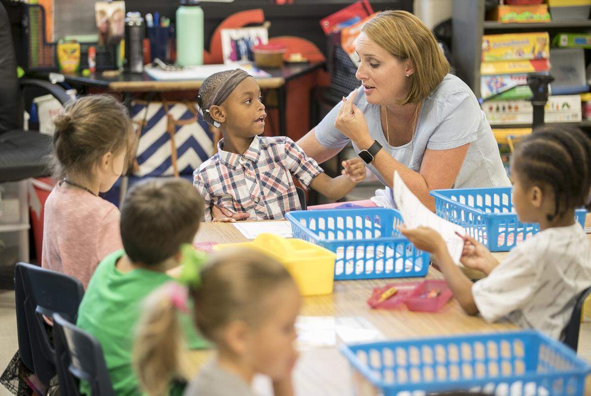 Prather Elementary School kindergarten teacher Sarah Fernandez works with Anthony Young on a writing and letter identifying worksheet.
