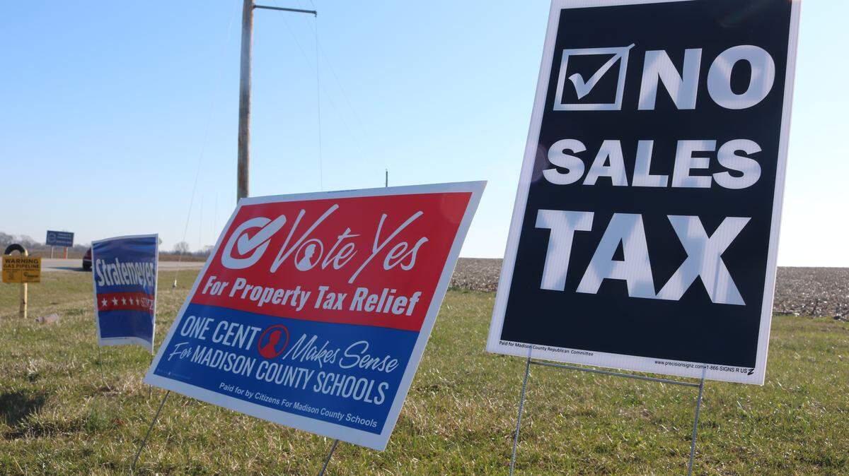 Picket signs at the Poplar Street and Route 143 roundabout in Highland. On March 20, voters in Madison County will cast their ballots for a third time on a sales tax that would benefit local schools. The left is a sign promotes the measure, while the right presents its opposition.