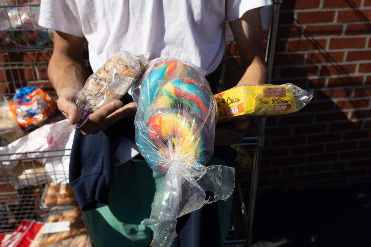 A food pantry patron holds bags of bread while waiting in line for service at the Community Interfaith Food Pantry in Belleville. “It says we can take three,” the patron said, “so I’m grabbing three.”