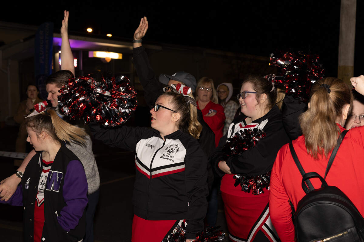 Cheerleaders with the Special Olympics Illinois wave as plungers line up to leap into a dumpster full of cold water in Collinsville Friday.