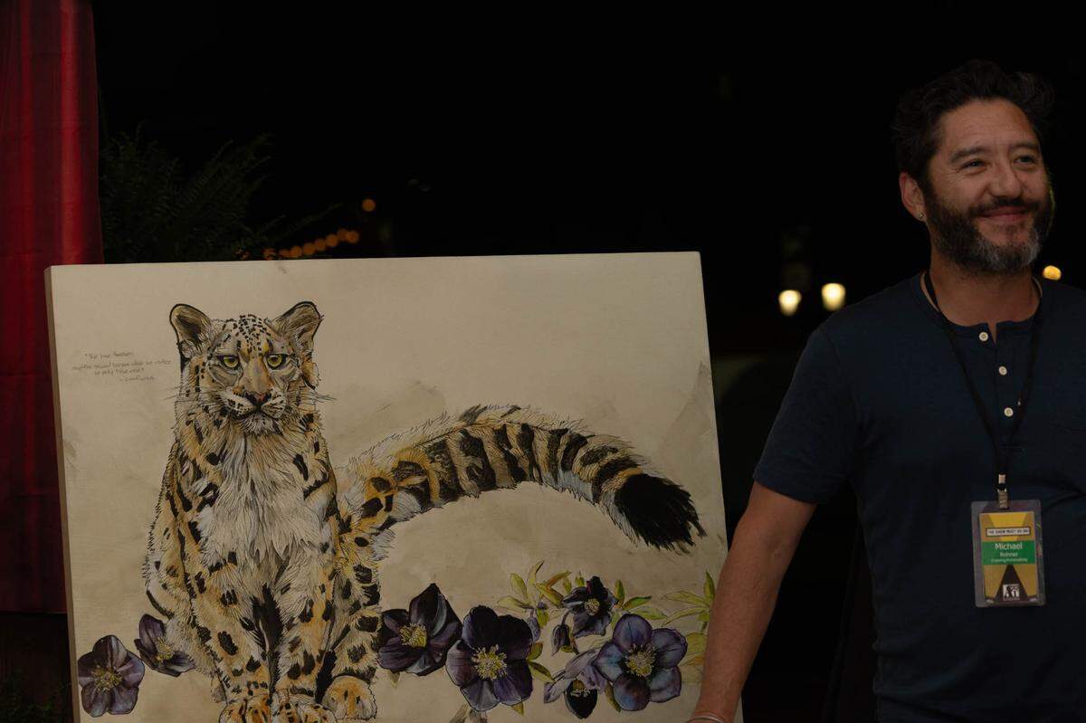 Michael Rohner smiles next to his painting “The Duality of Vulnerability” after winning a purchase award.