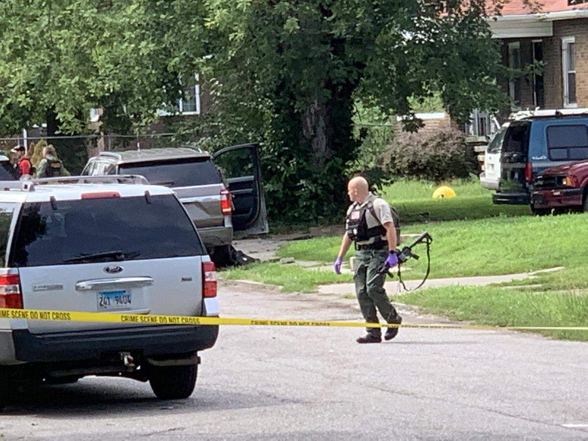 A law enforcement officer armed with a rifle walks from the crime scene Friday in East St. Louis.