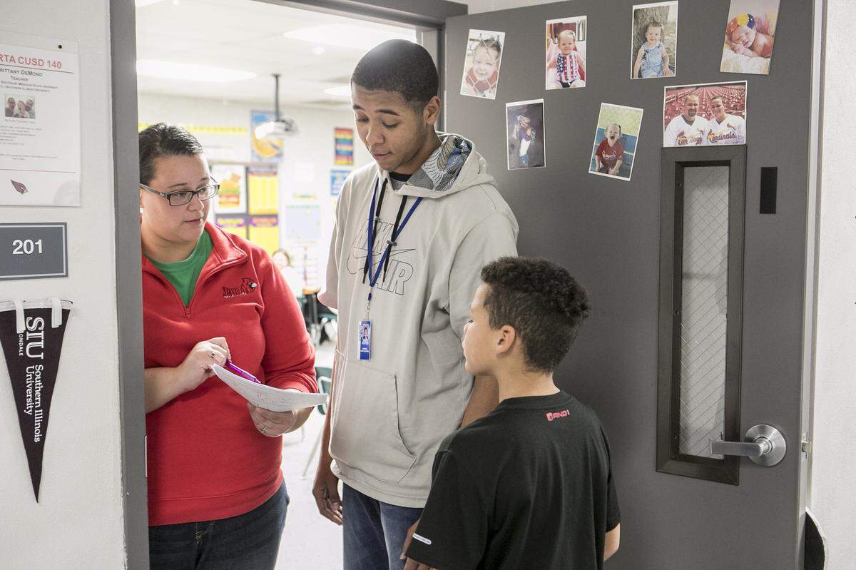 Brittany DeMond answers a question on fractions for Sparta High School senior Jonah Boston and third grade student Tyrell Charles. Boston was working on fractions with Tyrell as part of a program to introduce high school students to teaching.