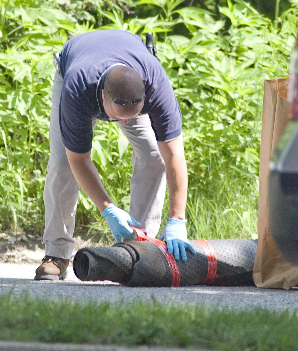 An Illinois State Police investigator secures the rug that was wrapped around a body found near the intersection of 29th Street and Morris Ave. in East St. Louis.