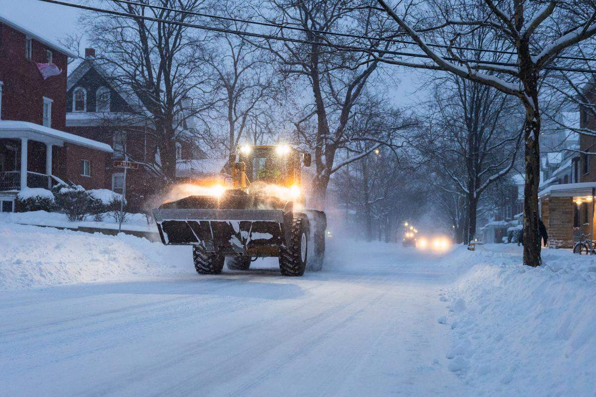 A tracker drives down West College Avenue during a snowstorm on Sunday.