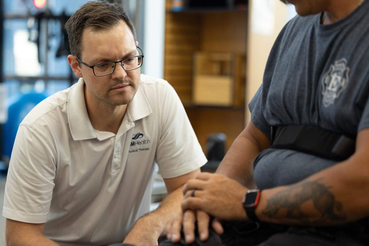 Physical therapist Kevin Murray watches as Brad Henke opens up the ReWalk app on his smart watch that allows him to use his exoskeleton legs. Should the watch fail or glitch, there are also controls on his electronic cane and his phone.
