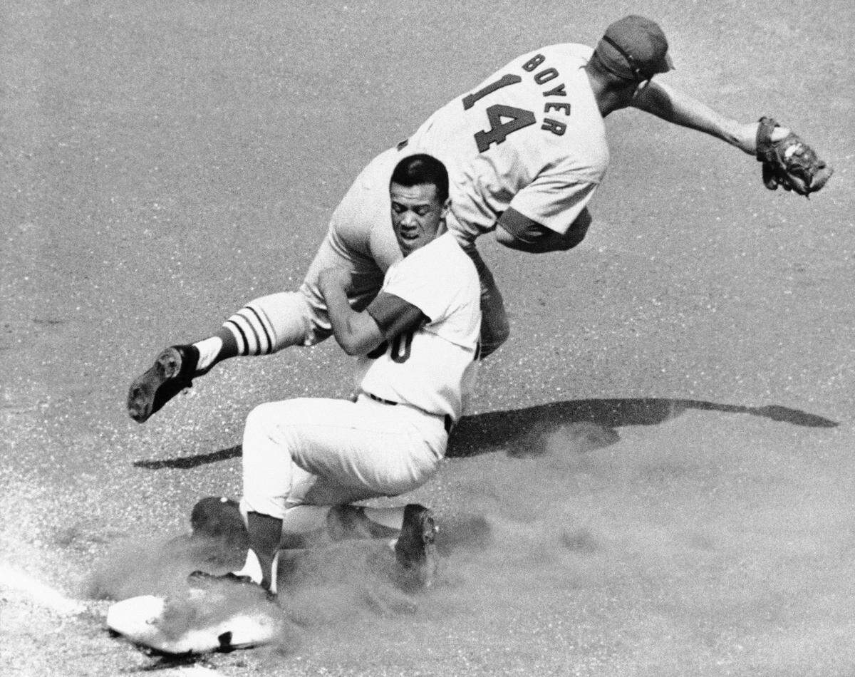 Third baseman Ken Boyer stretches for a throw while the Dodgers’ Maury Wills slides in.