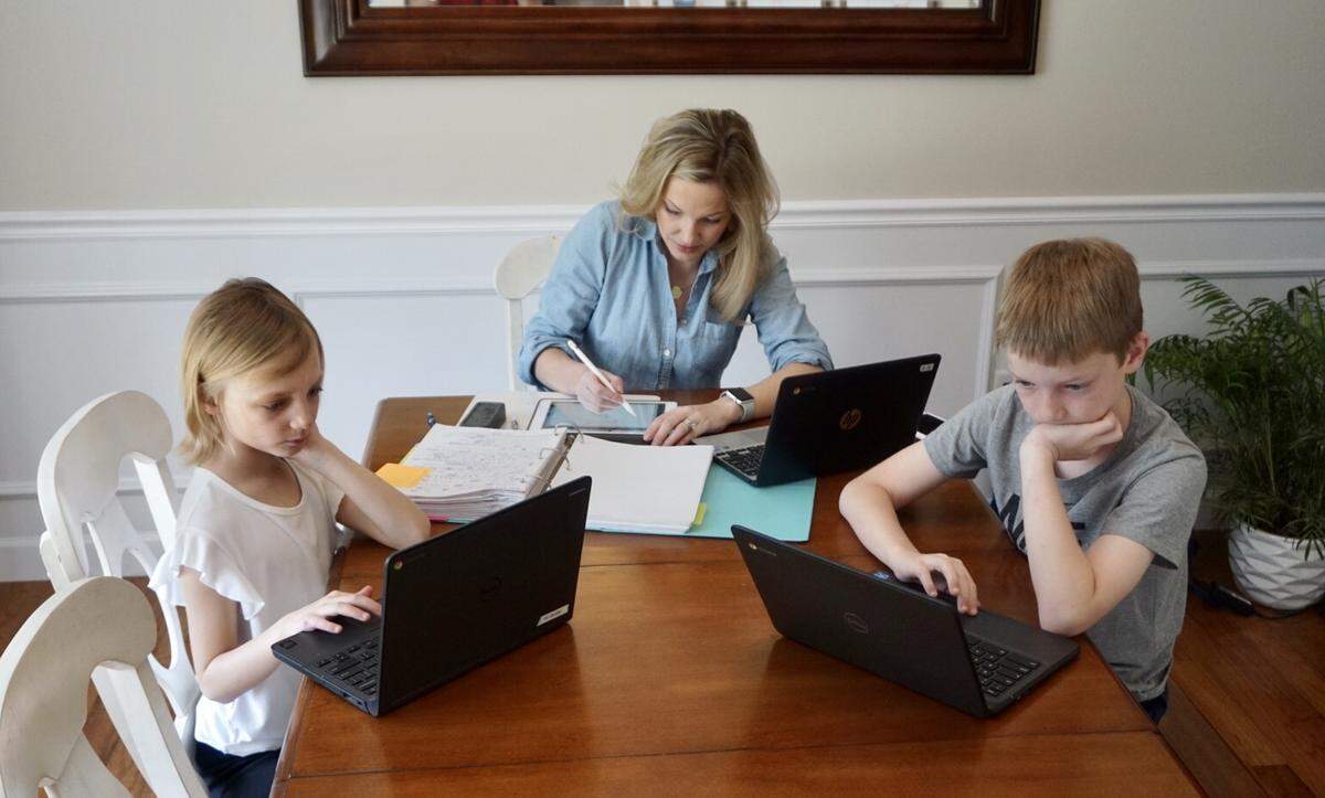 Belleville East High School math teacher Rebecca Schrader, center, works on lesson plans while daughter, Reese, 8, left, and son Mason, 11, do homework at their dining room table in Swansea.