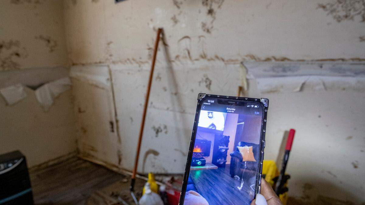 An East St. Louis homeowner shows a before photo of her basement family room that was flooded to the ceiling in July. The split foyer home has seen flooding before but never this bad and for this long, according to the homeowner.