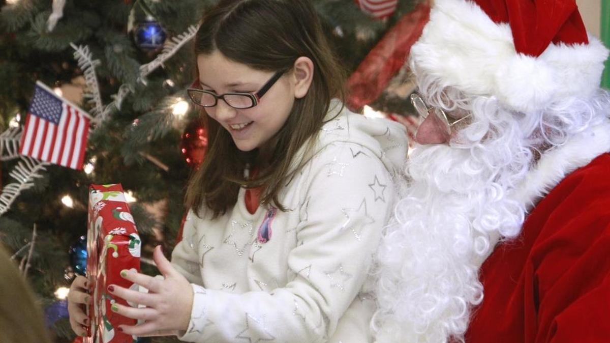 Kylie Poindexter, of Scott Air Force Base, flashes a smile after getting a gift from Santa Claus during an Operation Homecoming event coordinated for area children and those of parents at Scott Air Force Base which is nearby. Each child received three stocking stuffer gifts and one larger toy they got to choose, eat cookies, drink hot chocolate, visit with Santa and also get school supplies if they needed them. About a hundred children came to the event in the first hour.