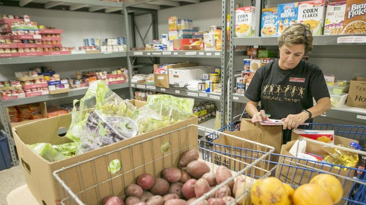 Community Interfaith Food Pantry volunteer Debbie Thacker fills an order for a customer.