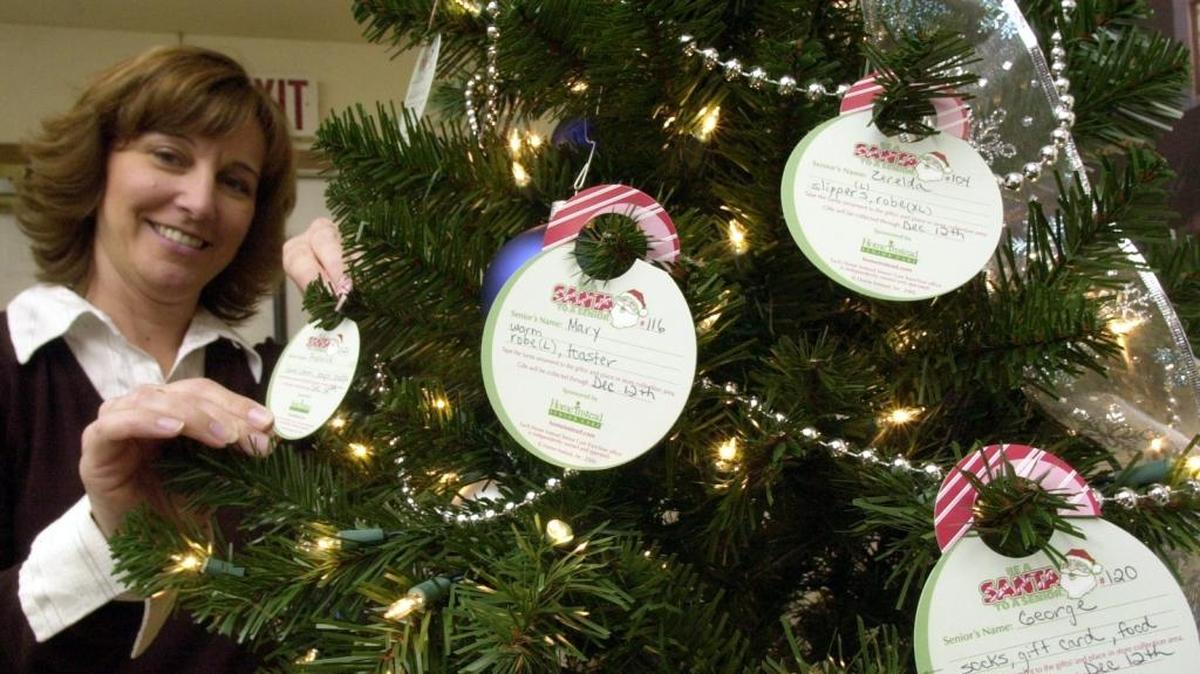 From the archives: Cindy Hill, a community service representative with Home Instead Senior Care, shows the “Be a Santa to a Senior” Christmas tree.
