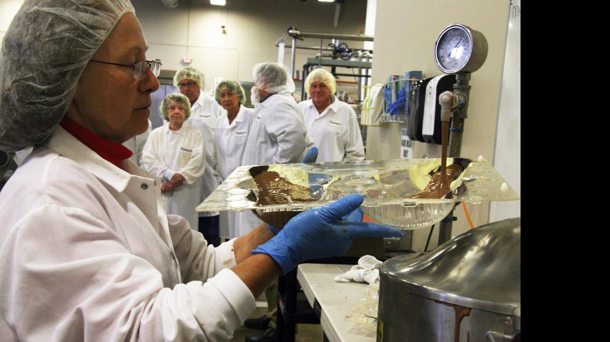 
Folks on a Bissinger's chocolate factory tour watch Paula Wilson fill a mold for solid chocolate Santas. Each weighs 1.5 pounds. Bissinger tours are usually Mondays, Wednesday and Fridays.
