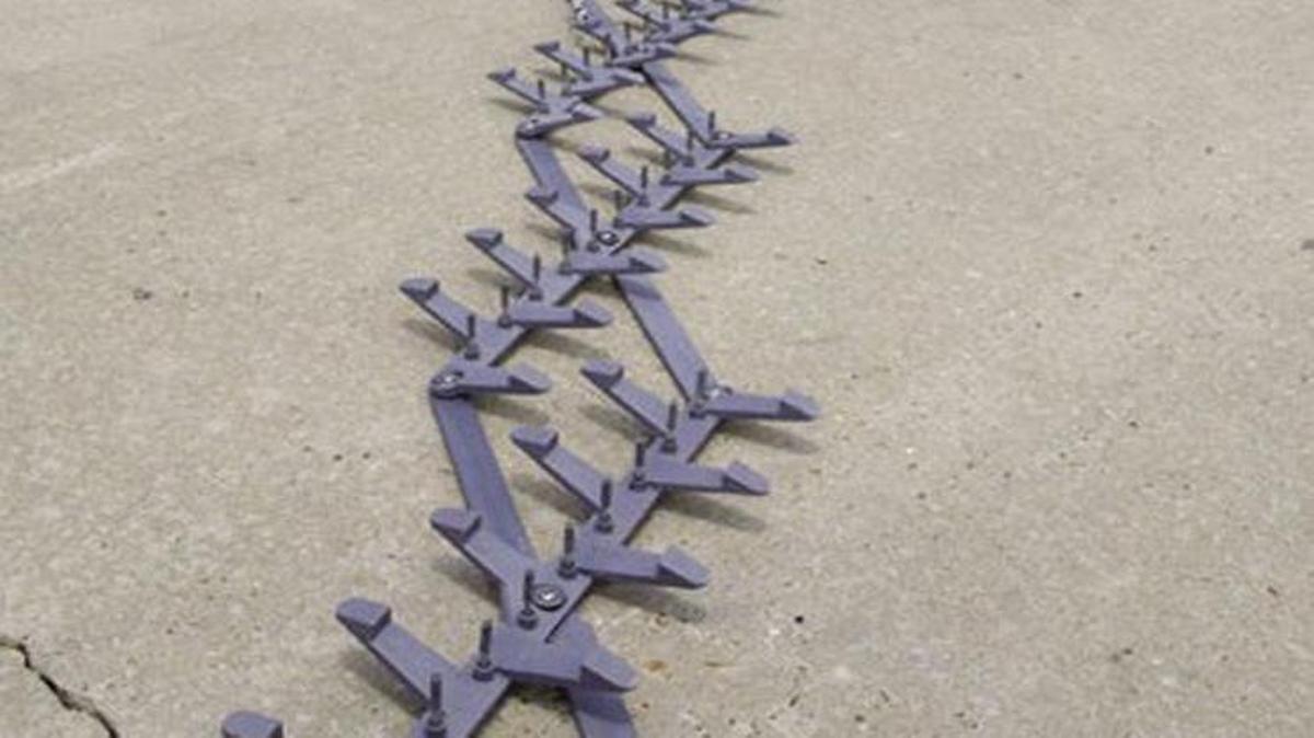 An officer demonstrates throwing out spike strips.