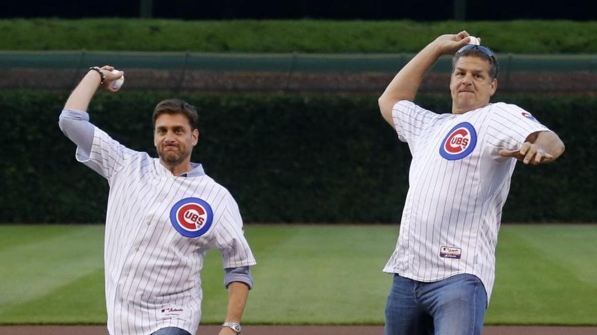 Sports radio personalities Mike Greenberg, left, and Mike Golic throw out a ceremonial first pitch before a baseball game between the Chicago Cubs and the Colorado Rockies on Tuesday, July 29, 2014, in Chicago.