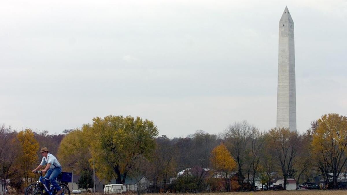 In this AP file photo, a young Mennonite rides his bicycle on U.S. Highway 68 West past the Jefferson Davis monument on Wednesday, Nov. 9, 2005, in Fairview, Ky. The towering monument marks the birthplace of Confederate President Jefferson Davis.