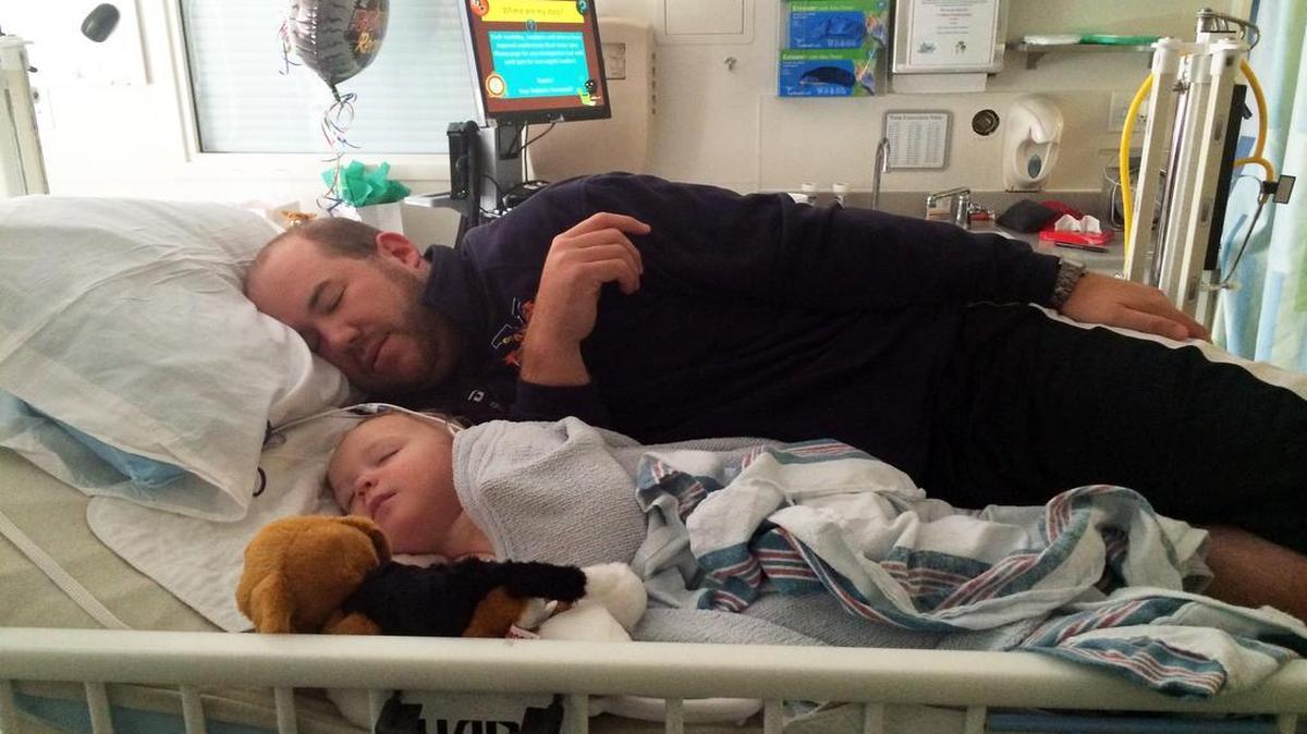 
Jason Murphy sleeps in the hospital bed next to his son Owen who had suffered a stroke.
