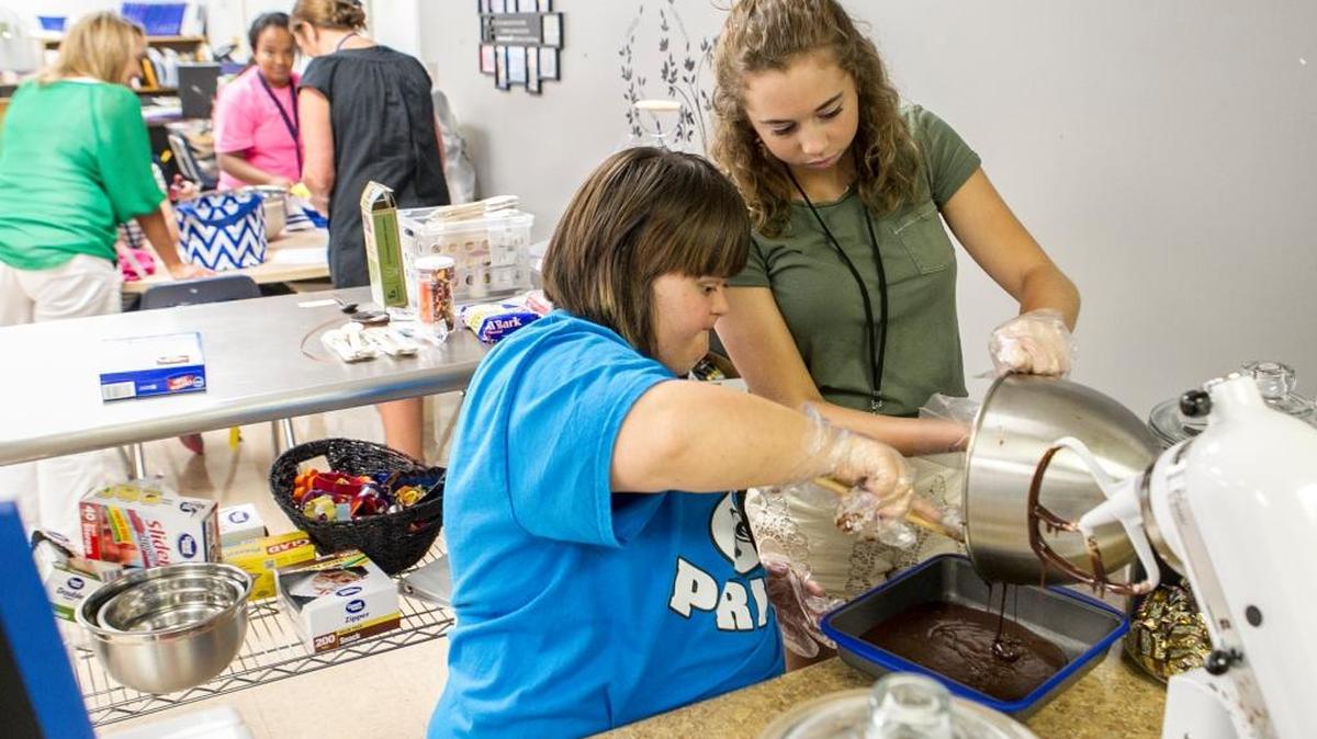 Student assistant Katelyn Jonak helps senior Taylor Ratajczyk make a batch of brownies in Gina Gunn’s special education classroom to sell at the Flight Crew Cafe at Columbia High School.