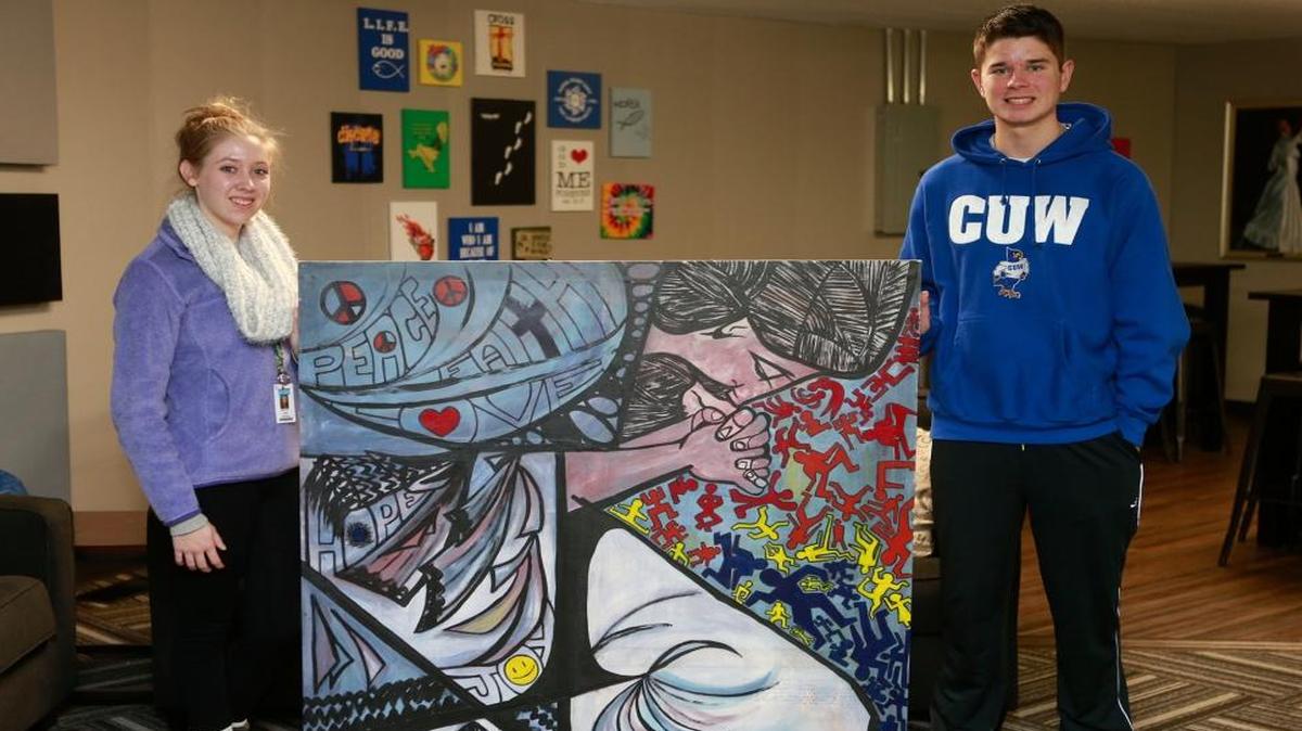 Students Lydia Aukamp and Marc Rodriguez pose with Keith Freeman's painting. They and other members of the Zion Lutheran Church youth group helped finish the piece, which the artist donated to the church.