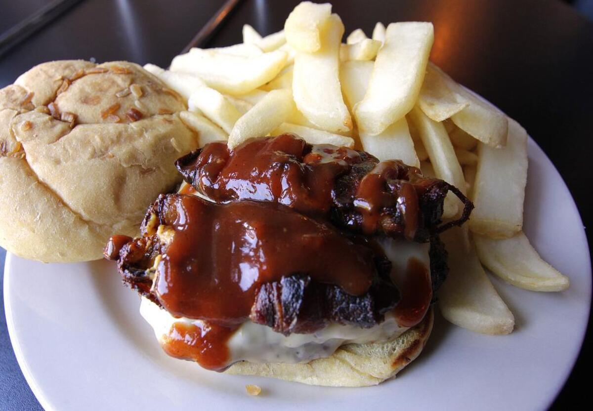 The Fifth Quarter Burger is topped with two bacon-wrapped, Cheddar-stuffed jalapenos and melted pepper Jack and drizzled with housemade sauce ($10 with one side).
