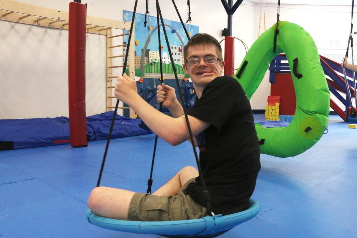 Matthew Torre, 25, of Highland, smiles at the camera while swinging at We Rock the Spectrum Edwardsville.