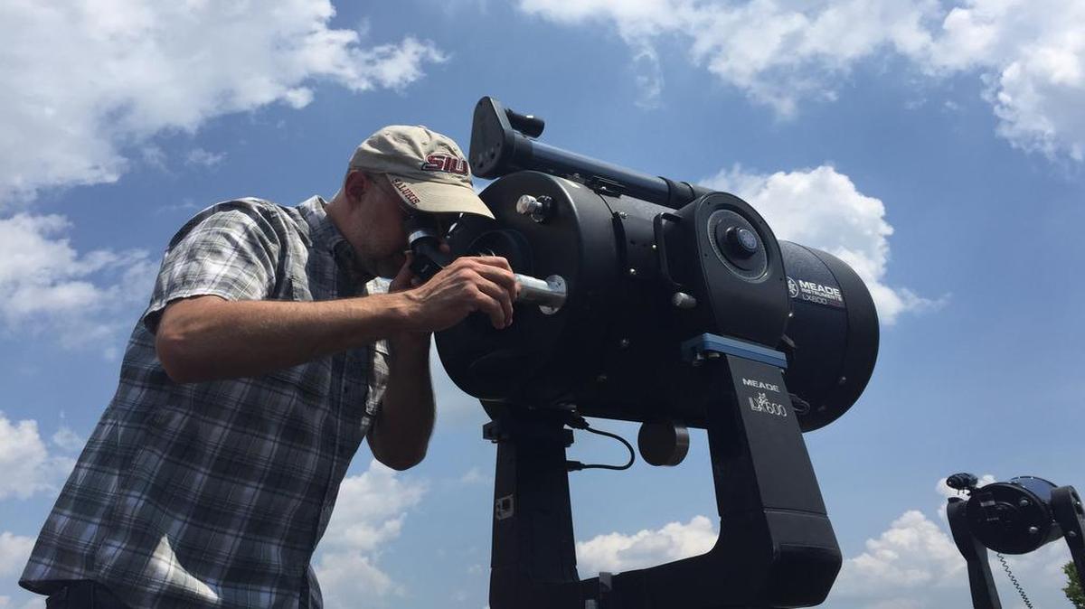Southern Illinois Eclipse 2017-2024 Steering Committee Co-Chair Bob Baer looks at a distant cell tower through a telescope at SIU’s astronomy deck.
