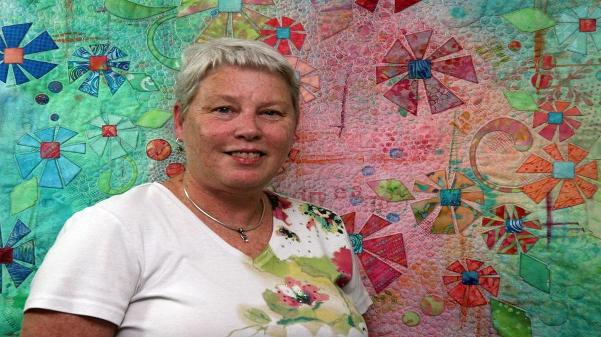 
Megan Knobeloch, of Belleville, stands in front of a mixed media quilt in progress that includes her hand-dyed fabric, applique flowers and hand-stamped designs. It’s called “Bodacious Blooms NO. 4 (Sweet Dreams.)” Most quilters will tell you that their favorite quilt is the one on which they are currently working, so I would say that No. 4 (Sweet Dreams) is my favorite.” 
