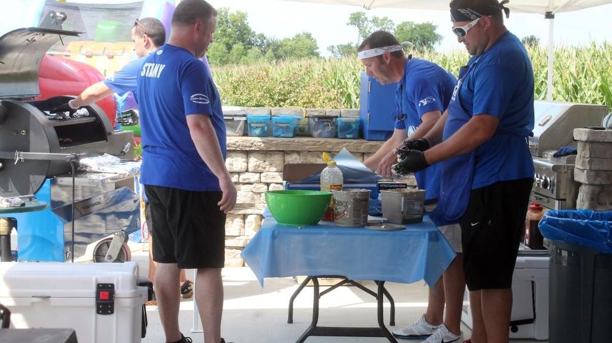 
Brian Combs mans the grill and Scott Stanifer, Brent Phelps and Jeremy Witt wrap ribs as they prepare for a party at the home of Aaron and Bonnie Gelly in rural Highland.
