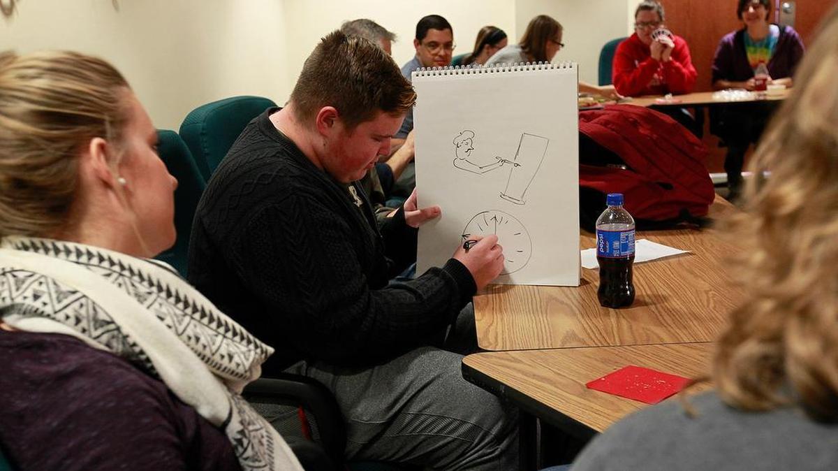 SIUE student Tyler Herron, of Belleville, center, draws clues for Caroline Cochonour, left, and Robin Cummings in a game of Pictionary at a German conversation table at Morris University Center. Playing the game in German helps them learn the language.