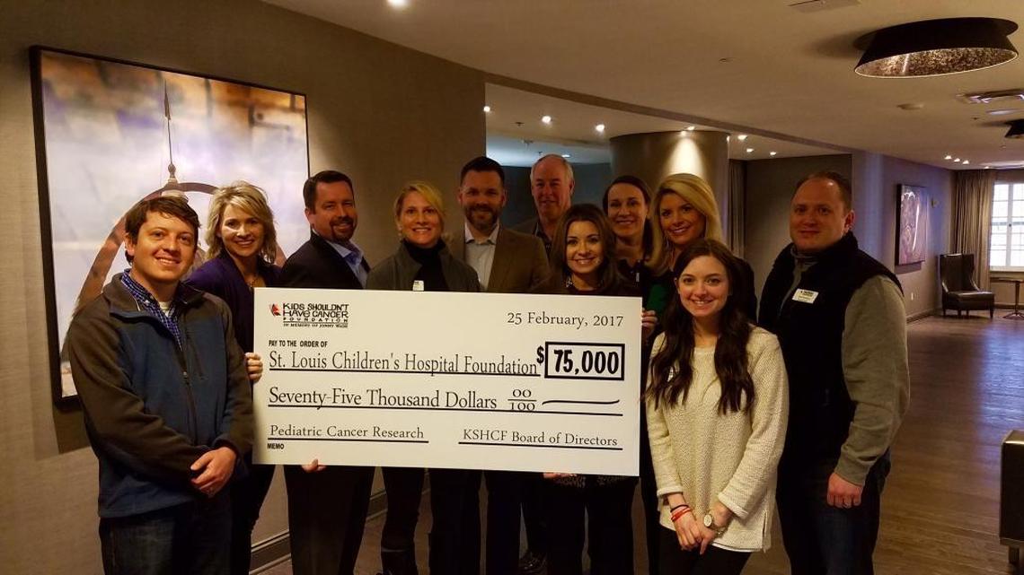 Jon Wade, third from left, and Kimberly Wade, fifth from right, and the board of the Kids Shouldn’t Have Cancer Foundation present a check to St. Louis Children’s Hospital on March 27.