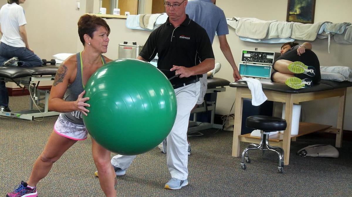 
Christy Belsom, of Belleville, works out with a stability ball during a physical therapy session with Brian Buescher at Phoenix Physical Therapy in Swansea. Christy, a personal trainer, was injured in a motorcycle accident in March. “She is the atypical patient,” Brian said. “When you go into an accident in the shape she was in, you come out a whole lot better.”
