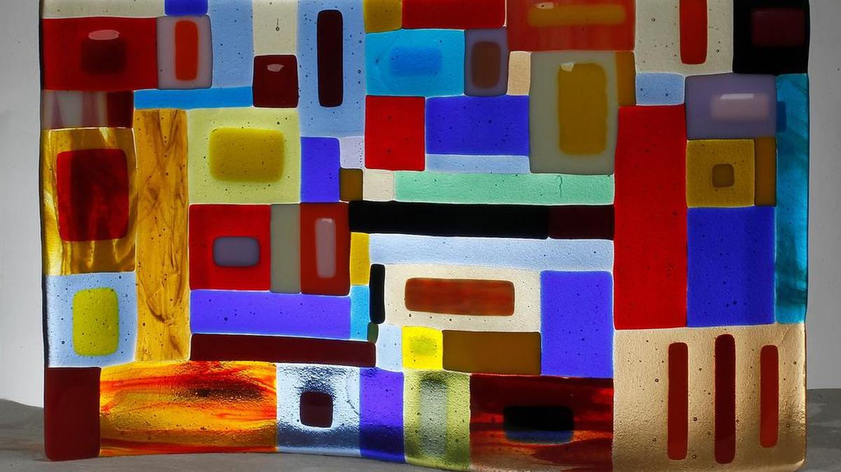 
Artist Nina Miller started with a clear glass sheet, arranged strips of colored glass on top of it, fired it in a kiln, shaped it into a mold, then fired it again to get this wavy piece.

