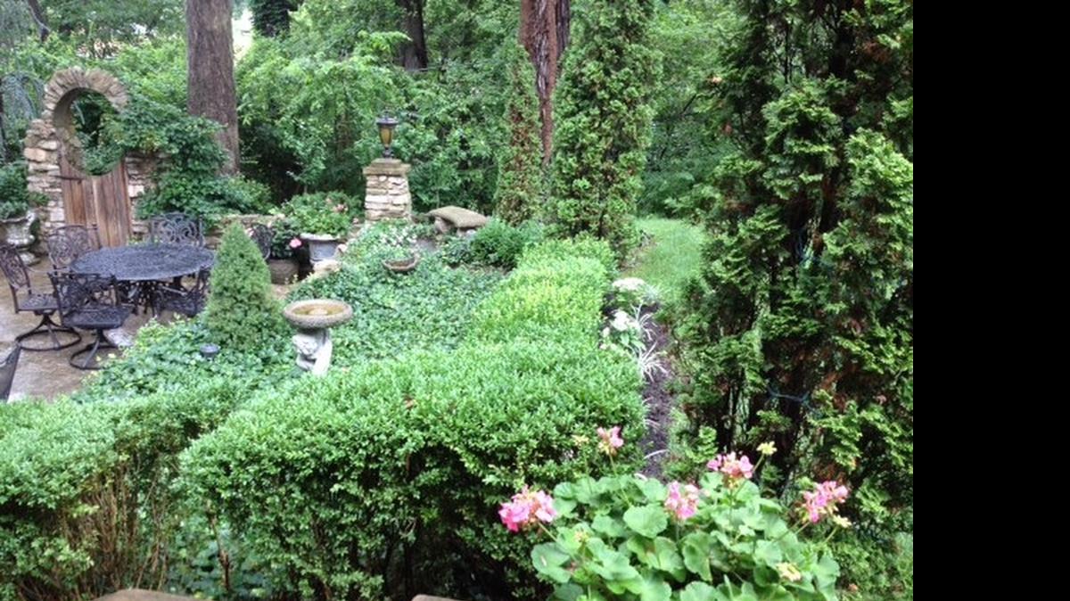 
The Schraders’ courtyard includes stone walls, arches and pillars, lots of plants, a seating area and a wooden gate that opens to the woods behind their home in Country Club Place.
