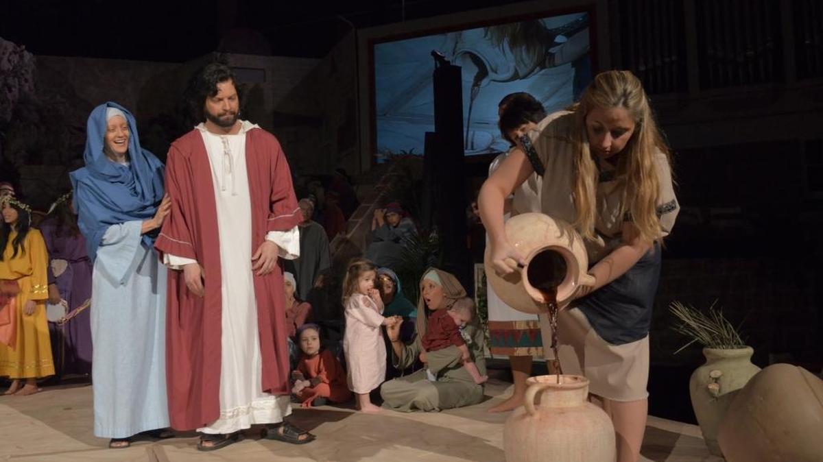 Jesus (Jamie Palmer) turns water into wine at the wedding feast of Cana. Phyllis Cahill portrays Mary, and Tara Renneke plays the servant pouring wine.