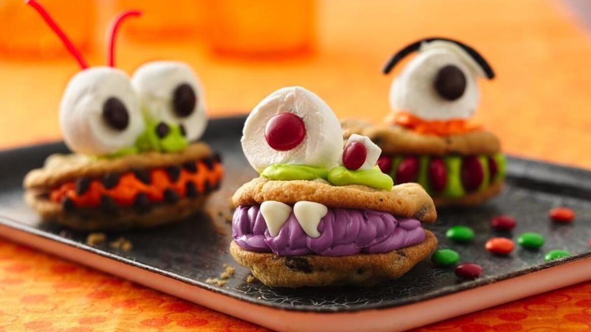 Grinning Monster Sandwich Cookies can be decorated in all sorts of ghoulish ways, from white chocolate chips fangs to marshmallow and M&M eyeballs.