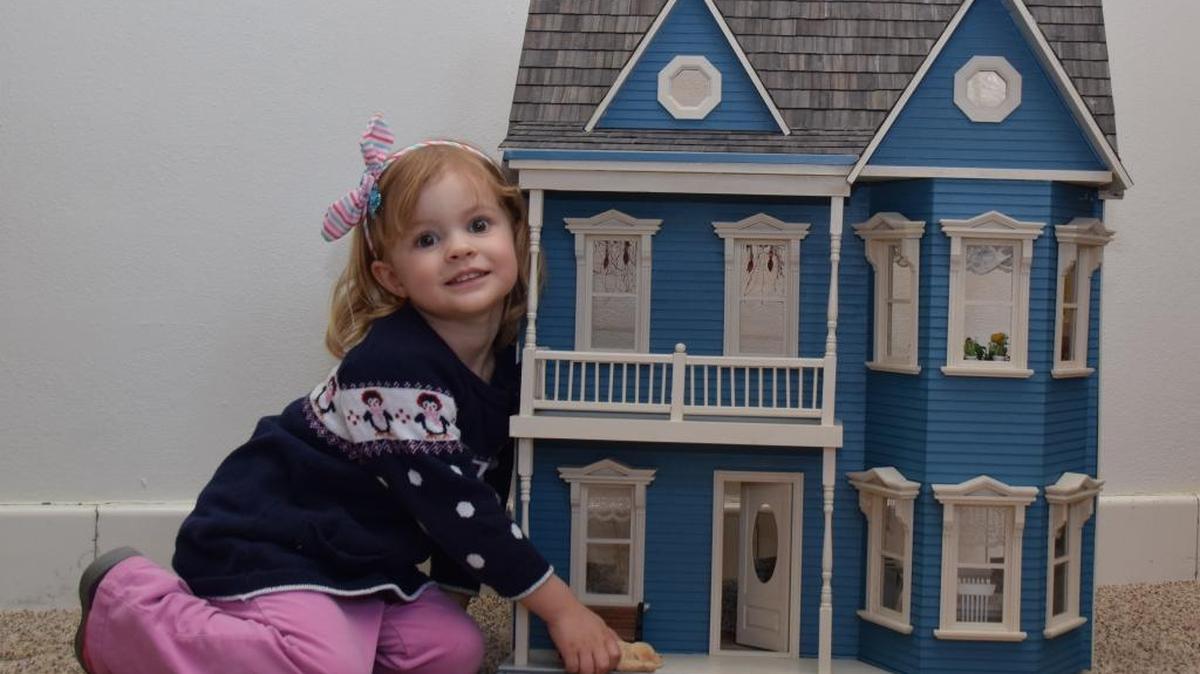 Ainsley Pipas, three year old daughter of Steve and Alaina Pipas of Belleville, admires a Victorian doll house which was hand-crafted by Nancy Bryant of Belleville. The furnished house will be raffled at the 2nd Annual Optimist Club of Belleville Luncheon and Style Show on Saturday