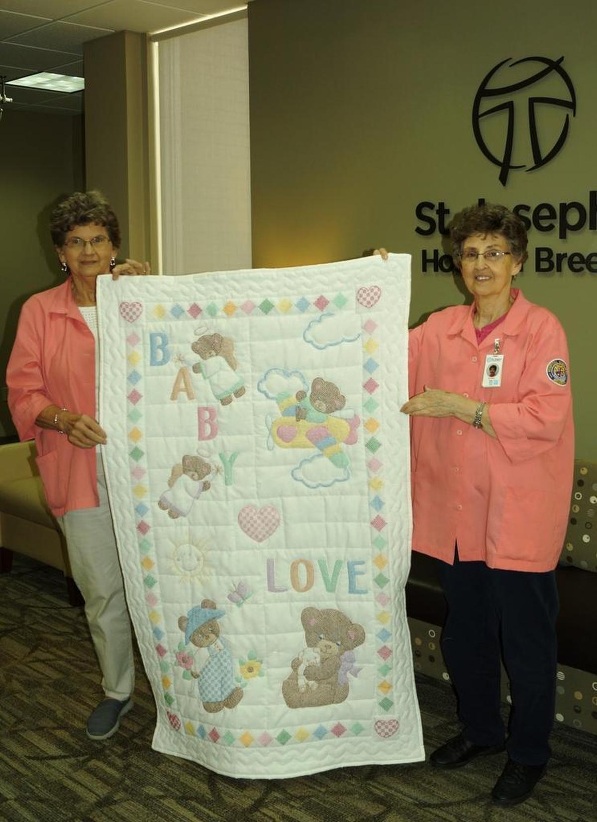 Mary Jane Fuhler, left, of St. Rose and Betty Richter, right, of Aviston display the “Baby Love” quilt. It is one of two quilts in the St. Joseph’s Hospital auxiliary quilt raffle on Thursday, Dec. 21.