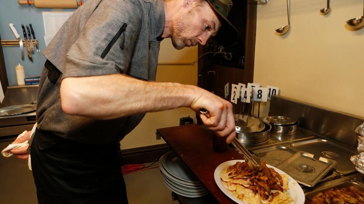 The Cabin at Judy Creek owner Justin Pickering prepares Napa’s Nachos, which is a plate of tortilla chips with house-smoked chicken or pork, carmelized onions, barbecue sauce, jalapenos and queso ($7).