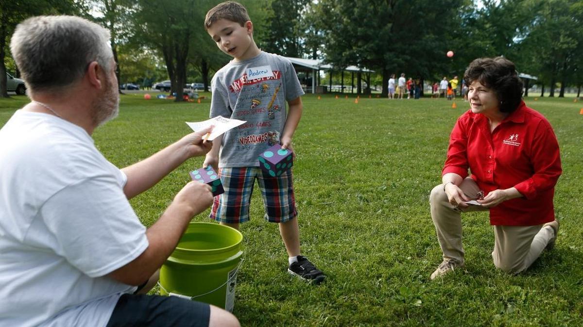 
From left, big brother Todd Smith, and little brother Andrew Smith, 9, chat with Barb Cempura, president of Big Brothers Big Sisters of Southwestern Illinois, while playing Yahtzee at a recent picnic at Moody Park in Fairview Heights. The organization is looking for more male mentors.

