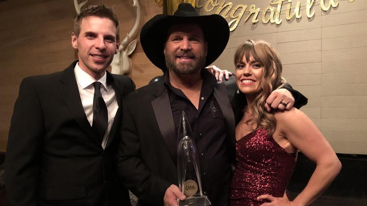 Amanda Valentine and Jesse Tack received their CMA trophy from Garth Brooks.