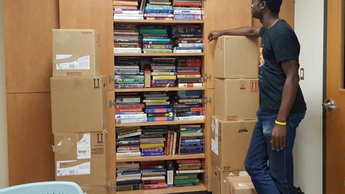SIUE graduate student Philip Alabi looks at some of the 1,000 textbooks he’s collected to ship to his alma mater in Nigeria. Now, he’s trying raise enough money to send them there.