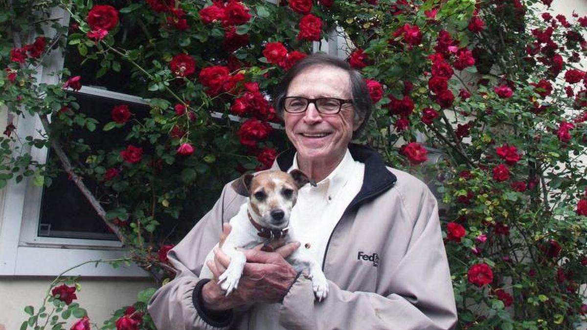 
Robert Teahan, holding his Jack Russell terrier Tippy, has a rose bush that has grown taller than the top of his garage in Fairview Heights.
