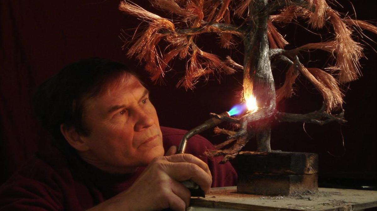 
Artist Wayne Tricklein uses a blow torch to heat the metal used in a tree sculpture. 

