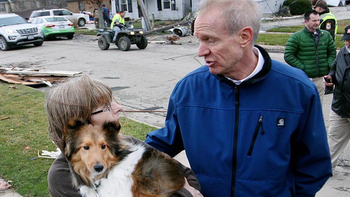 Illinois Gov. Bruce Rauner comforts Julie Wielgopola and her dog, Kirby, on Wednesday while touring the town of Napalm, in northern Illinois, a day after storms producing tornadoes moved through much of the Midwest.