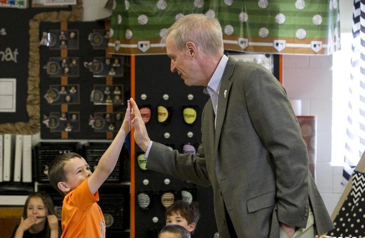 Illinois Governor Bruce Rauner gets a high five from Kindergarten student Miles Denny during his visit to New Baden Elementary school Monday.