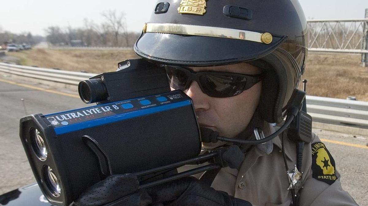 An Illinois State Police trooper uses a laser radar speed gun to clock motorists from the Black Lane overpass above Interstate 55/70.