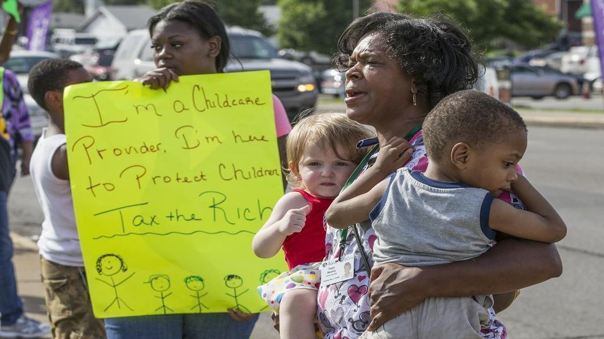 
Childcare provider and foster parent Fazio Beverly holds DeShawn and Rayven two foster chidren she is planning to adopt. She stated that, if she adopts the children she will lose chidcare benefits after the age of three. Previously she would have had childcare benefits through the age of 12 availabe. Childcare providers, parents, and other concerned community members protest Governor Rauner’s shortfall in funding for childcare services, public health programs for children, after school programs and the Child Care Assistance Program, which supports low-income working parents, are expected to deny child care services.
