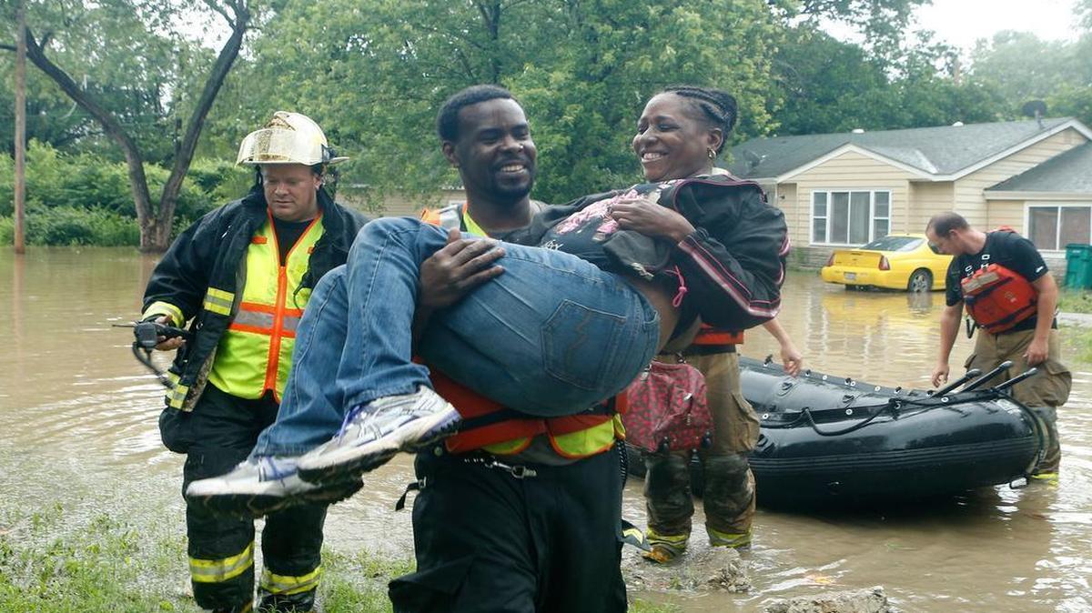 
An emergency worker Robin Shield carries Robin Shield onto dry land. Shield's home on North 61st Street in Centreville was flooded on Friday afternoon.
